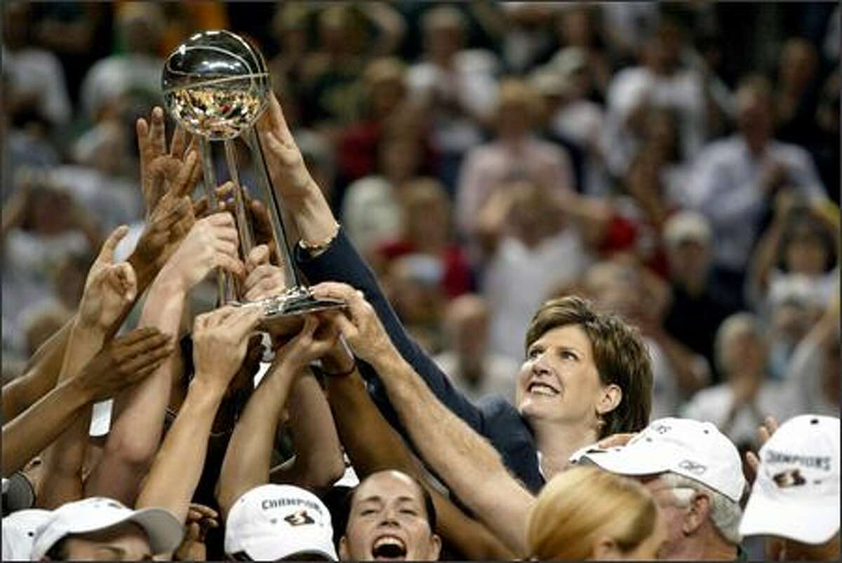 The Storm's Anne Donovan, holding the championship trophy with her players, became the first female coach to win a WNBA title.