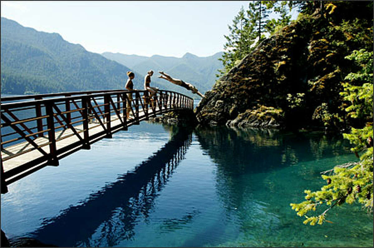 Anaka Helseth, 19, of Bothell, dives into a popular swimming hole on Lake Crescent from a bridge on the Spruce Railroad Trail.Schenker: After walking on the Spruce Railroad Trail around Lake Crescent and seeing no one, I had just about given up on getting anyone walking across this bridge, much less diving off, when Anaka Helseth and her friends showed up. Sometimes patience pays off.
