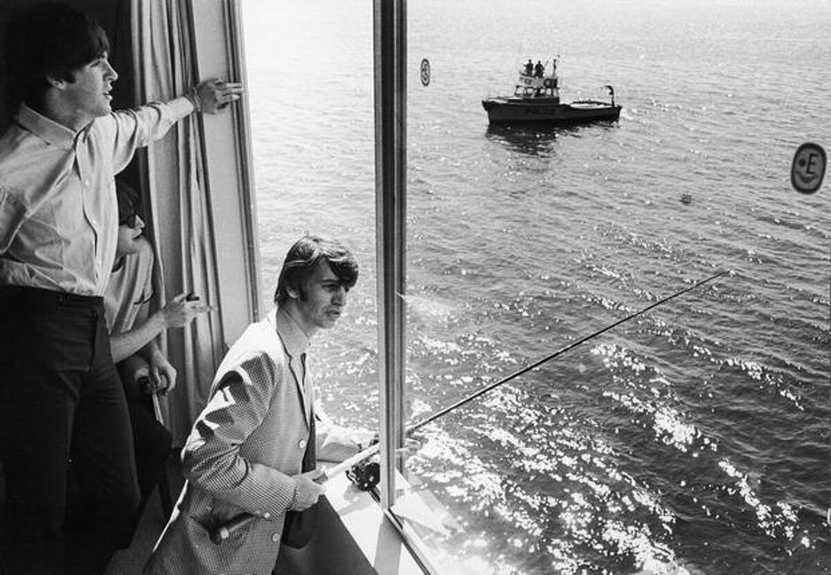 Ringo Starr fishes out an Edgewater Hotel window in Aug. 1964. Paul McCartney, left, and John Lennon watch. (William Lovelace/Express Newspapers/Getty Images)