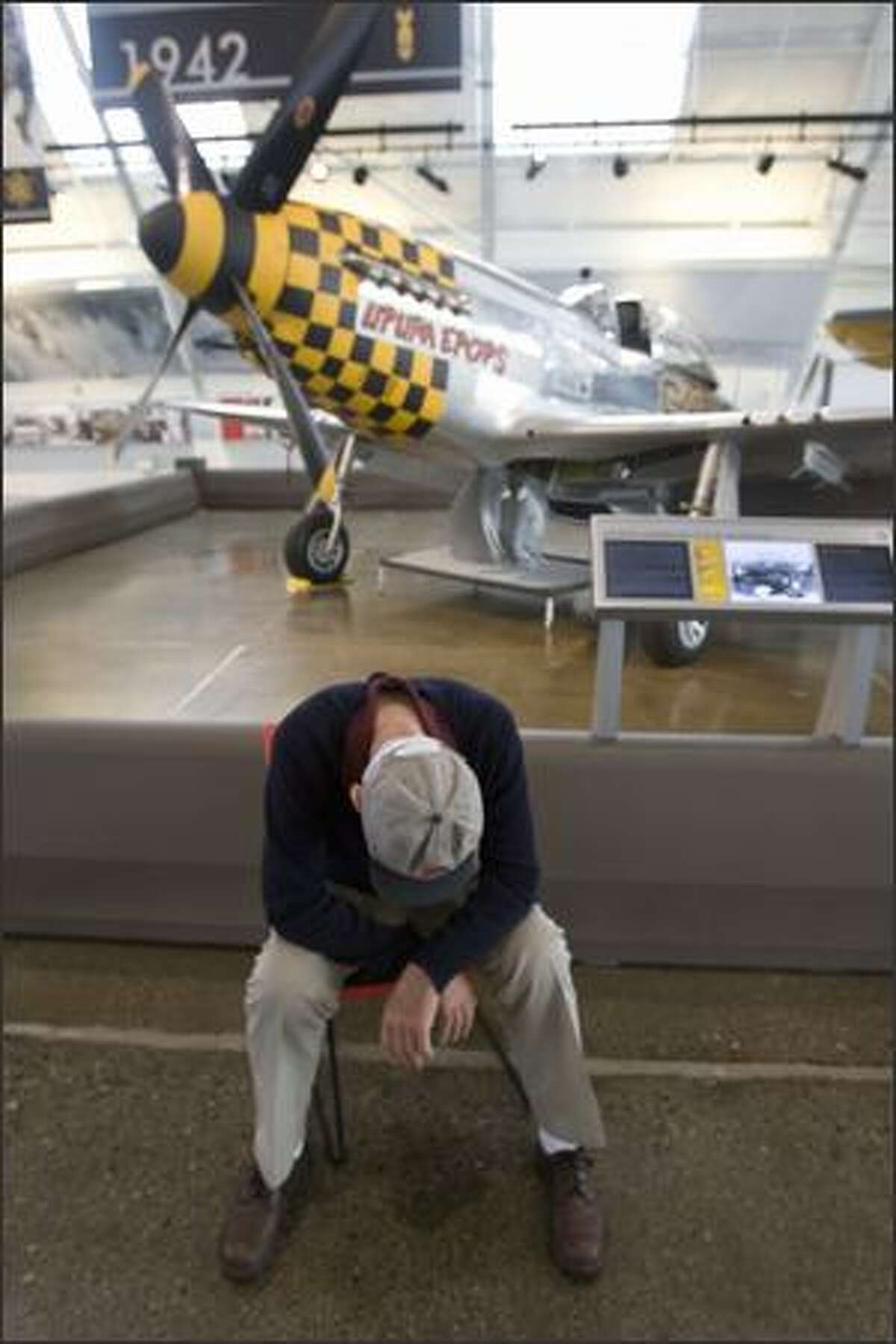 Harrison "Bud" tordoff, who flew more than 1,000 hours of combat in WWII and piloted the P-51 Mustang, behind him, against the Germans, takes a quick nap after talking to a group of visitors.