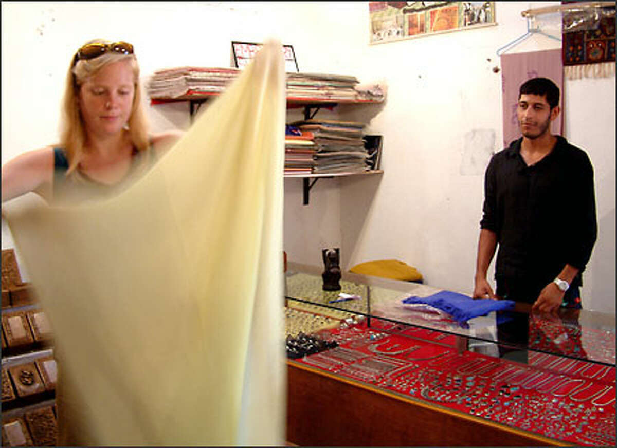 Tariq Ahmed Wani watches as Katrin Lepik of Seattle decides how much money to offer him for one of his pashmina shawls. A native of Kashmir, he sells pashmina items to tourists in the Indian state of Goa.