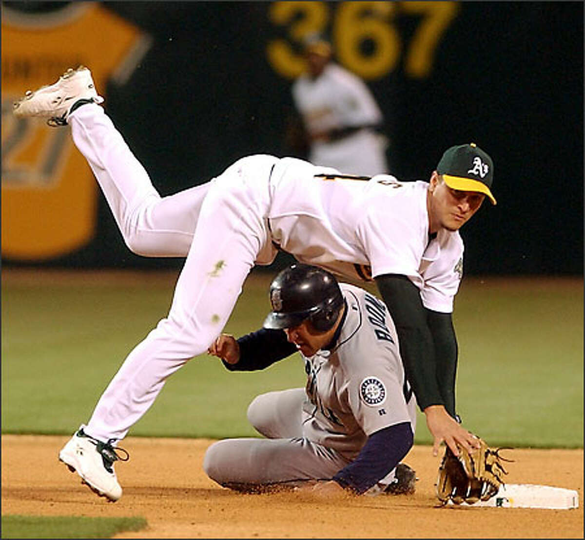 Oakland second baseman Mark Ellis falls over Boone, his Mariners counterpart, completing a double play that ended the fourth inning.