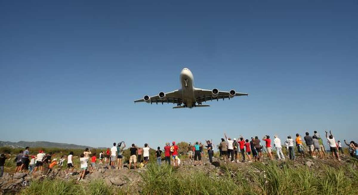 People watch as an Airbus A380 flies over the Indian ocean island of La Réunion during an exhibition flight before landing at the Roland-Garros airport on November 11, 2009 near the city of Saint-Denis-de-la-Réunion. The local airline company Air Austral has ordered two of the aircraft.