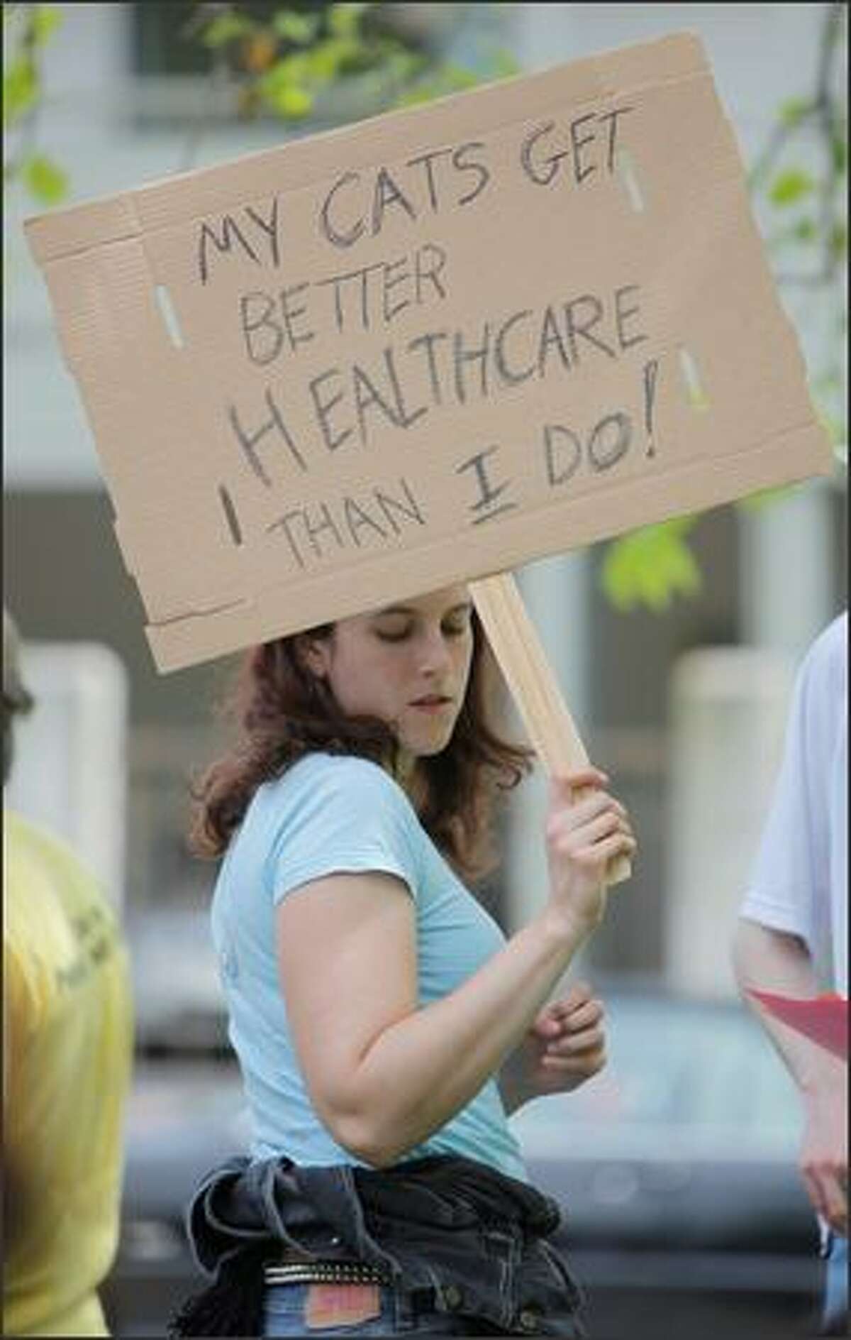 Sarah Silverman of Seattle holds a sign stating that her cats get better health care than she does.