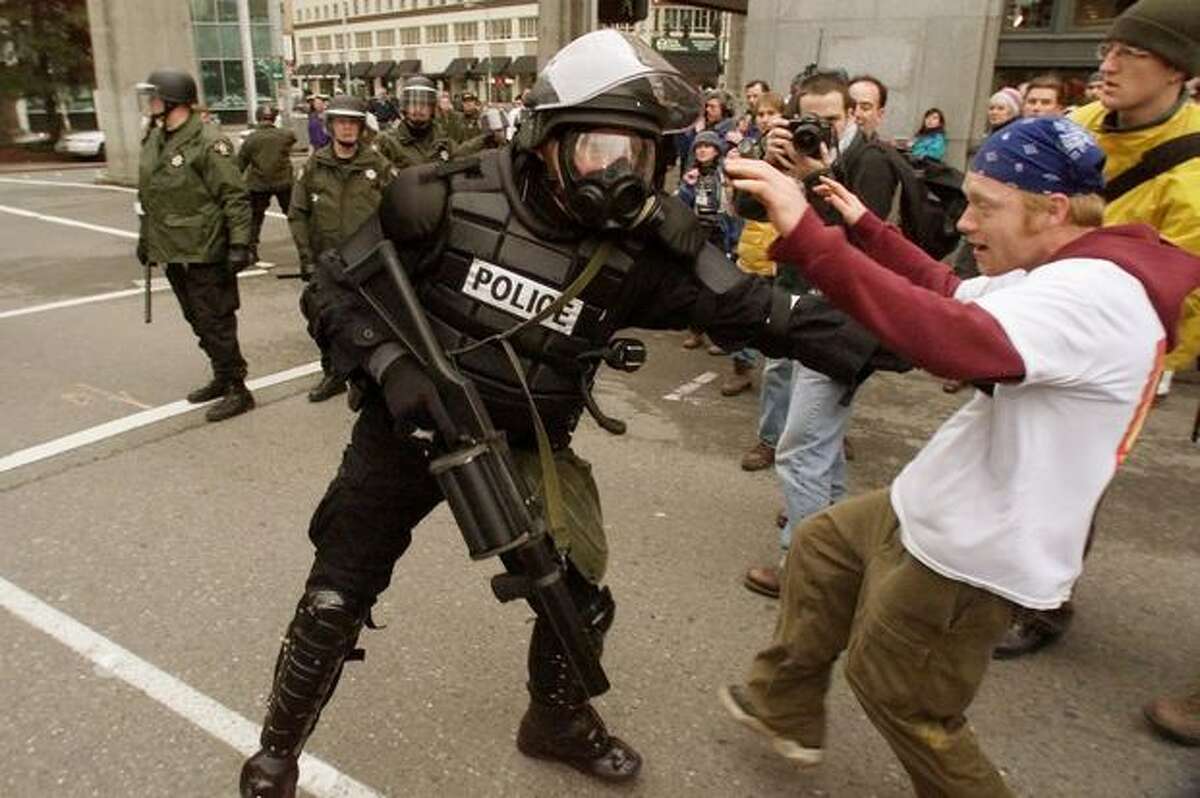 A Seattle police officer shoves protester Jody Hutchinson as police march down Virginia Street on Dec. 1, 1999.