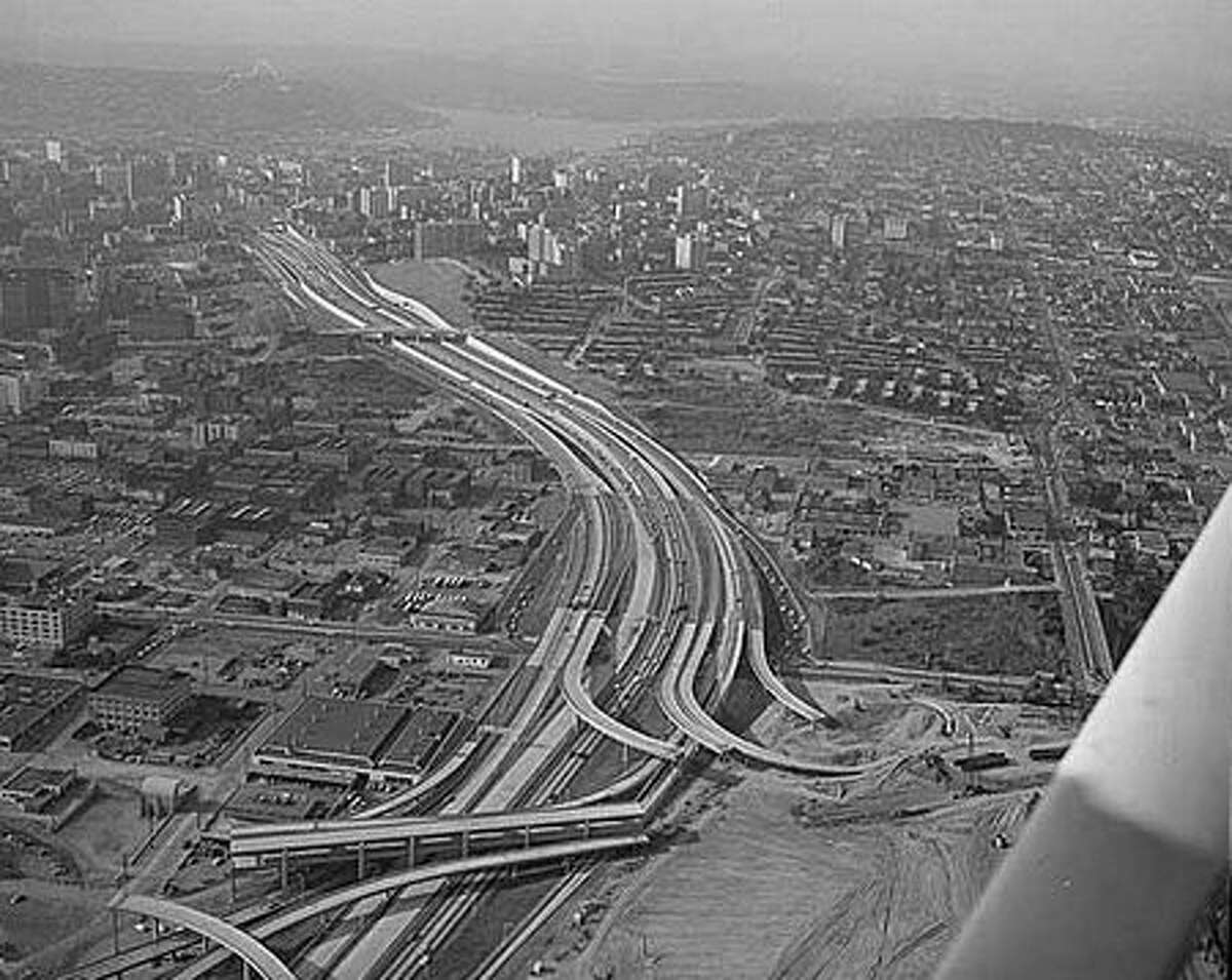 Aerial of freeway construction, Seattle, 1967. Construction of the Tacoma-Seattle-Everett freeway, which opened to traffic in December 1962, took up 6,600 parcels of land, 4,500 of them in Seattle. In 1958-59, the Washington State Highway Department paid homeowners fair market value for their homes, then auctioned the buildings for either removal or salvage. (Seattlepi.com file/MOHAI)