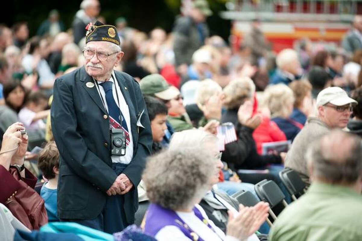 Veterans rise to applause as their song is played during a Memorial Day service.