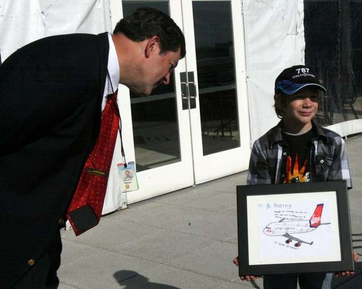Harry Winsor, 8, presents an airplane drawing to Dave Reese, senior manager of visitor relations for Boeing Commercial Airplanes, on the strato deck of the Future of Flight Aviation Center, in Mukilteo. Boeing invited Harry and his family to visit after initially botching a response to a drawing he sent to the company.