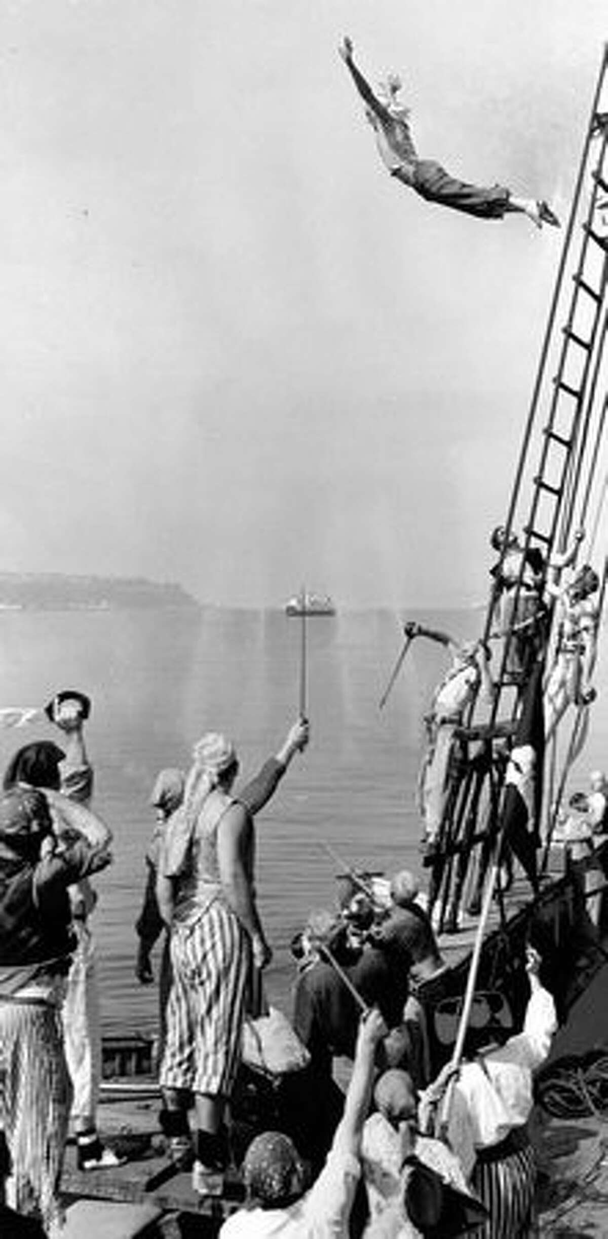 A Seafair pirate dives from the rigging of the three-masted schooner Wawona in Elliott Bay, July 1953.