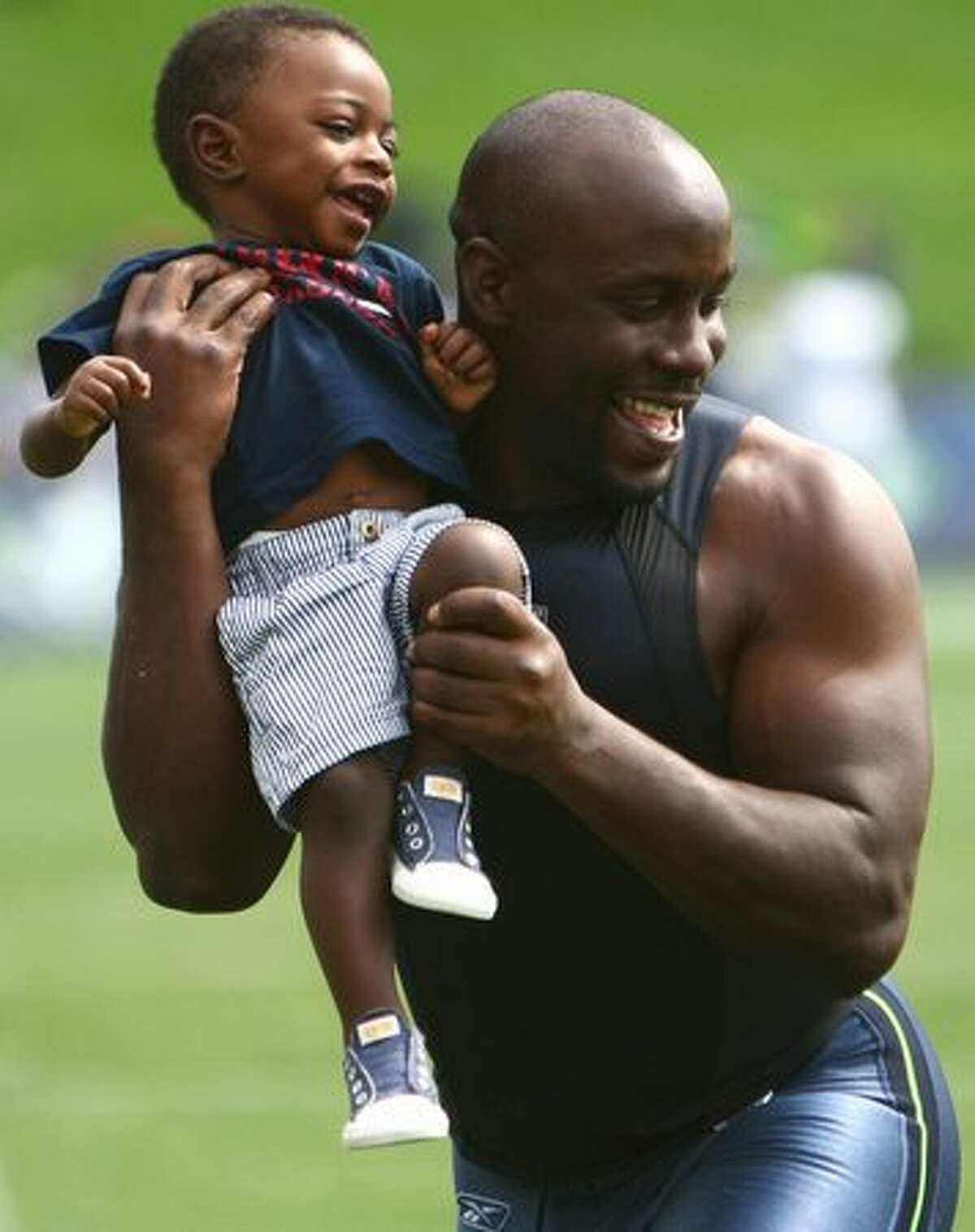 Seattle Seahawk Leon Washington carries his son Noel, 1, after a team practice at the Virginia Mason Athletic Center in Renton.