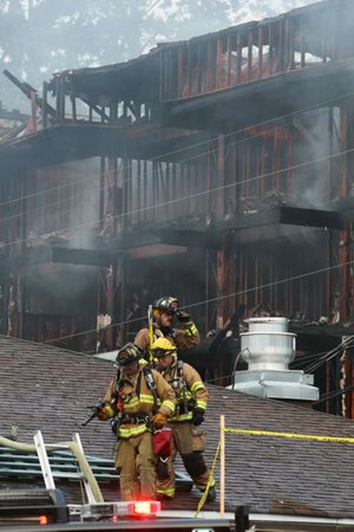 Firefighters descend from a neighboring rooftop.