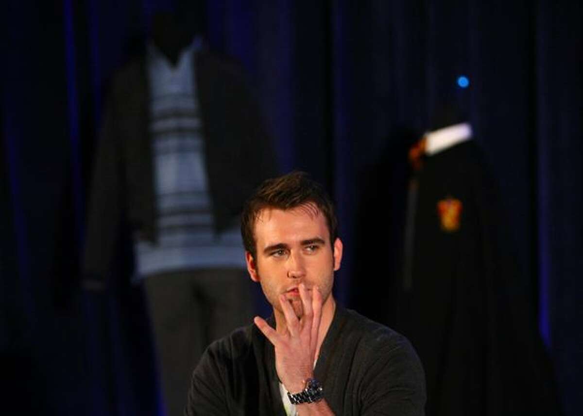 Actor Matthew Lewis, who plays the character Neville Longbottom in the Harry Potter films, speaks onstage at the Pacific Science Center. Behind Lewis are two of his costumes from the film.
