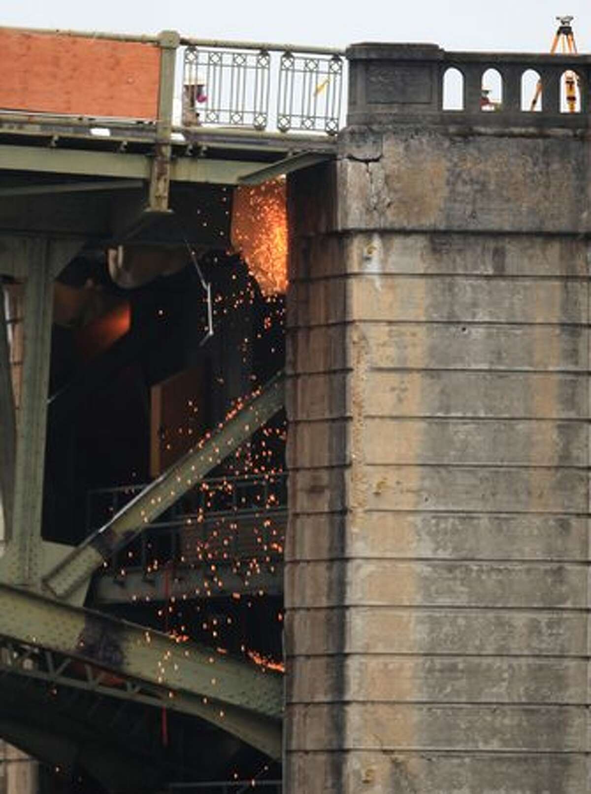 Sparks fly as as the west leaf of the South Park Bridge is cut from the west bridge tower.