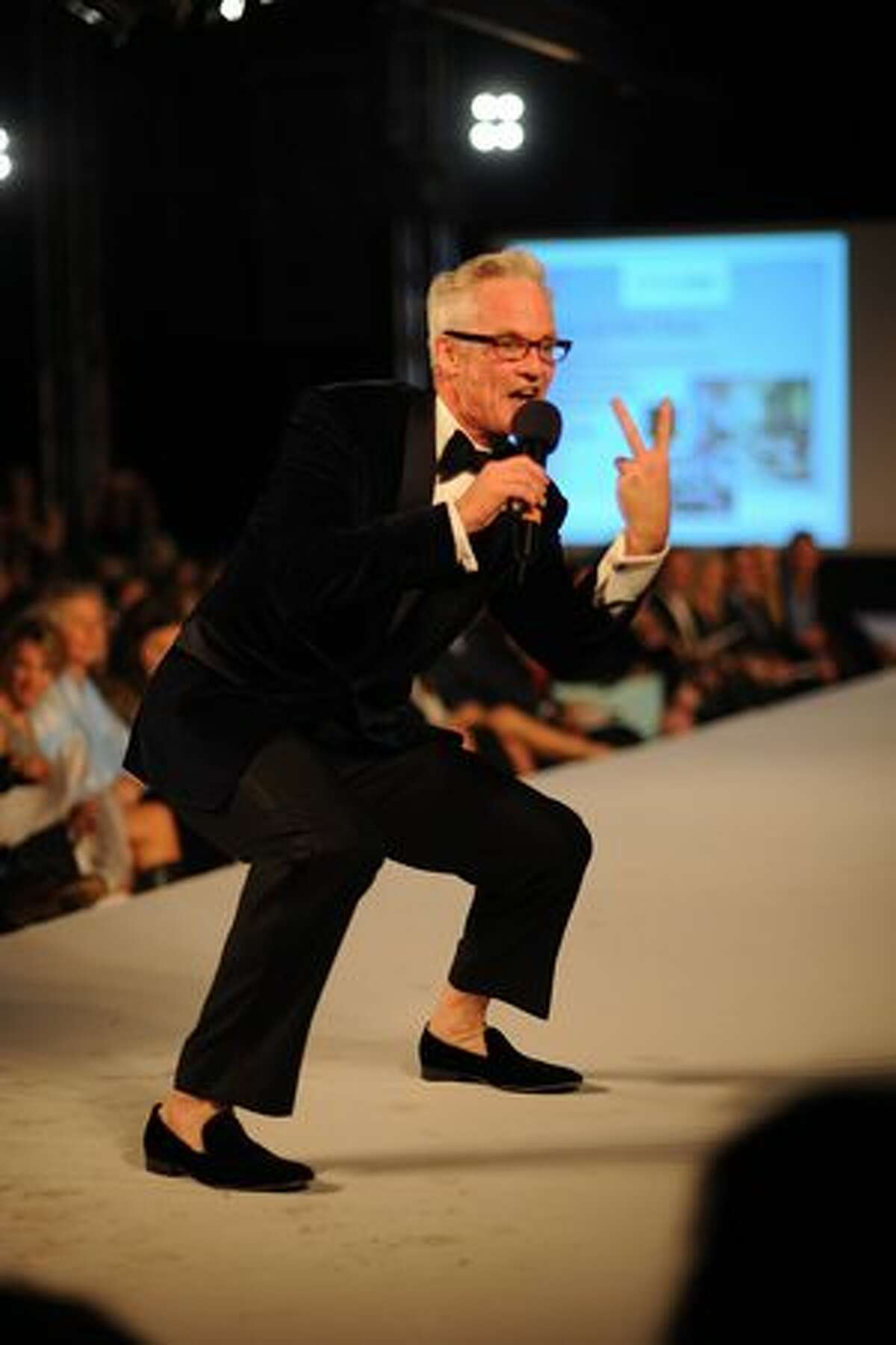 John Curley gives an energetic, if not athletic, performance as he auctions off items at the 7th Annual Fashion First show. Auction items were sold to raise money for Rise N Shine.