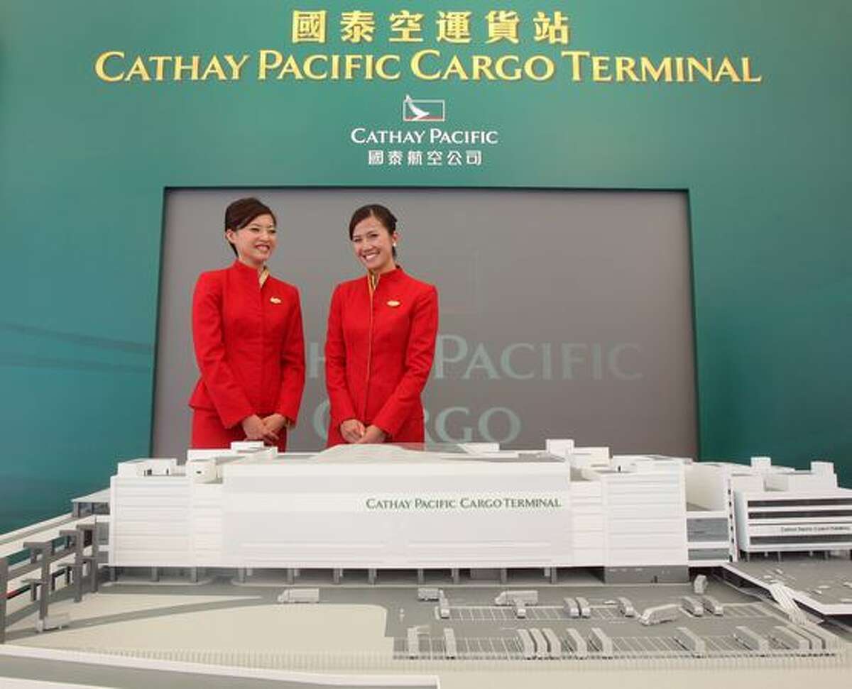 Models pose beside a model of the new Cathay Pacific cargo terminal at Hong Kong International Airport
