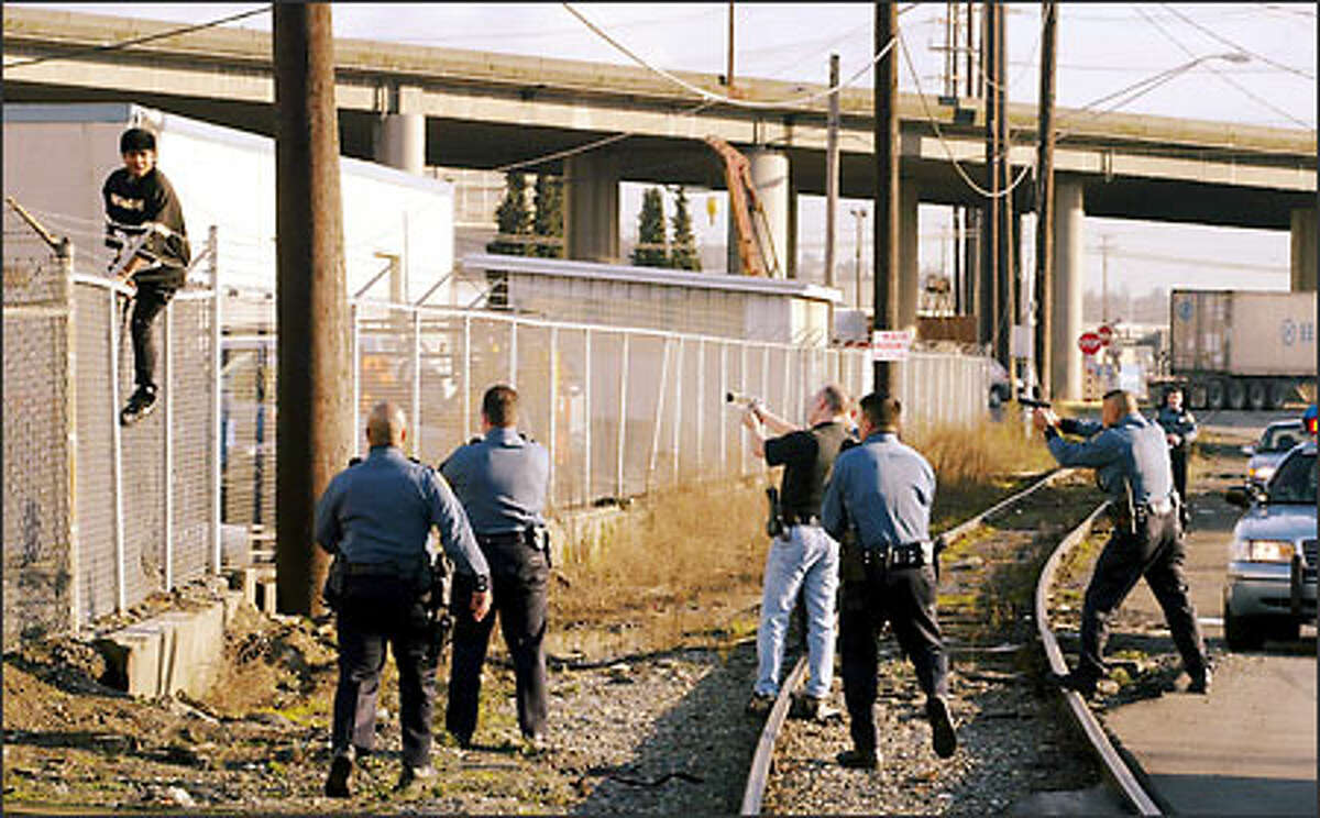 A 16-year-old suspect in a car theft climbs a fence as Seattle police close in. The youth is suspected of stealing a car.Schenker: "I was on a 'ride-along' with a Seattle police officer and things were very slow when a call came over the radio about a car theft in the area. After a number of high-speed twists and turns, she stopped and told me to stay back by the car. Well, I couldn't resist being curious, so I cautiously ran toward the action anyway. As I came around a corner this is what I witnessed -- the suspect in the act of trying to evade the police and getting caught at the top of a fence."