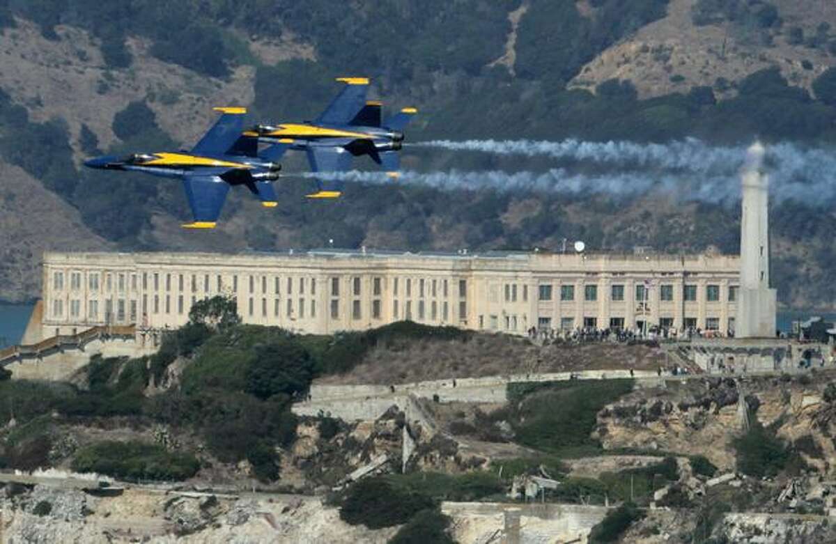 Two U.S. Navy Blue Angels F/A-18 Hornets fly over Alcatraz Island, in San Francisco while practicing for Fleet Week.