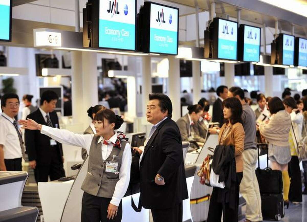 Passengers check in at an Japan Airlines desk at the newly opened international terminal building of the Tokyo International Airport.