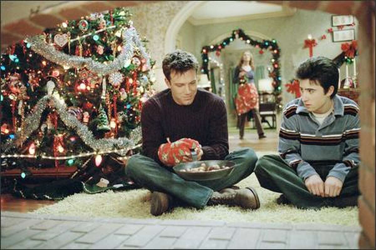 Drew Latham (Ben Affleck, left) and his "adopted" brother Brian Valco (Josh Zuckerman) enjoy the old Christmas tradition of roasting chestnuts on an open fire, as their "mother" Christine (Catherine O'Hara) looks on.