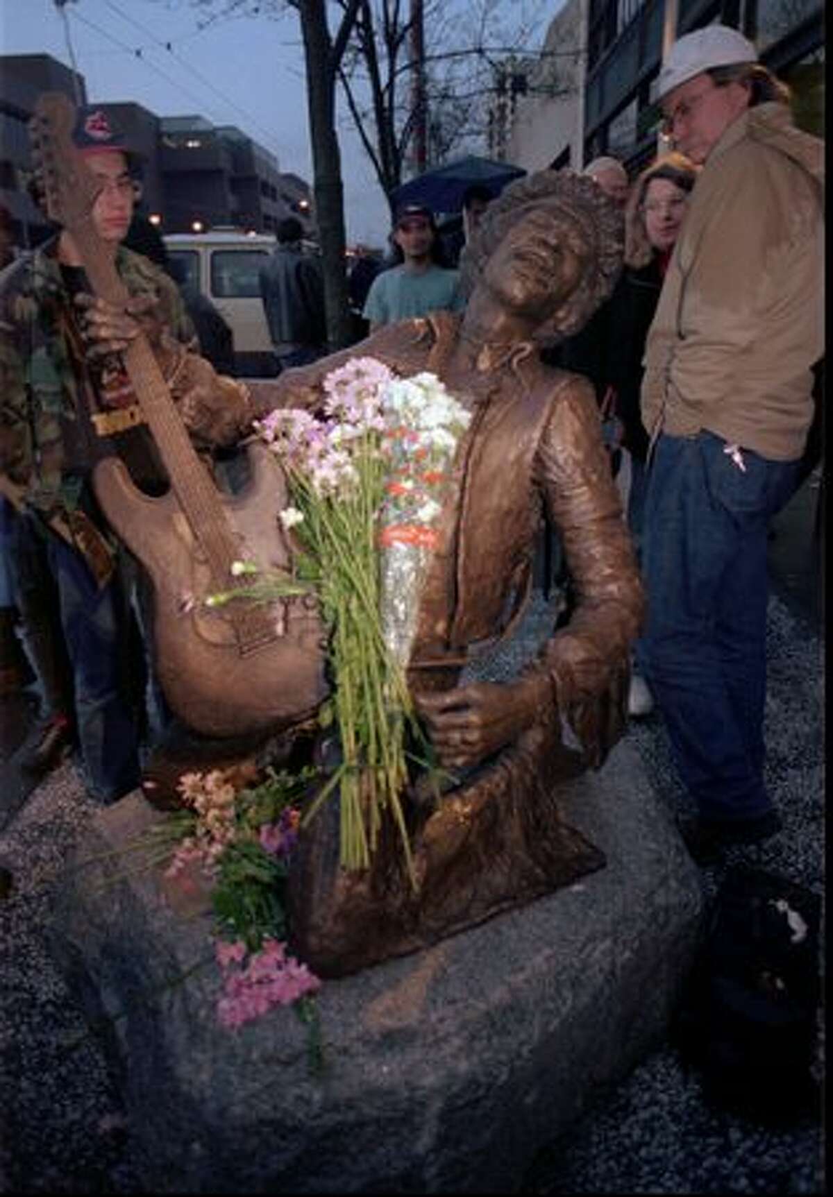 Fans view a bronze statue of the late guitarist Jimi Hendrix at an unveiling ceremony Tuesday, Jan. 21, 1997, outside the corporate offices of AEI Music in Seattle. AEI Music commissioned the statue to memorialize Hendrix's 1970 Fender Stratocaster guitar, which AEI owned, as part of their "Legends Collection" of music memorabilia. (AP Photo/Robert Sorbo)