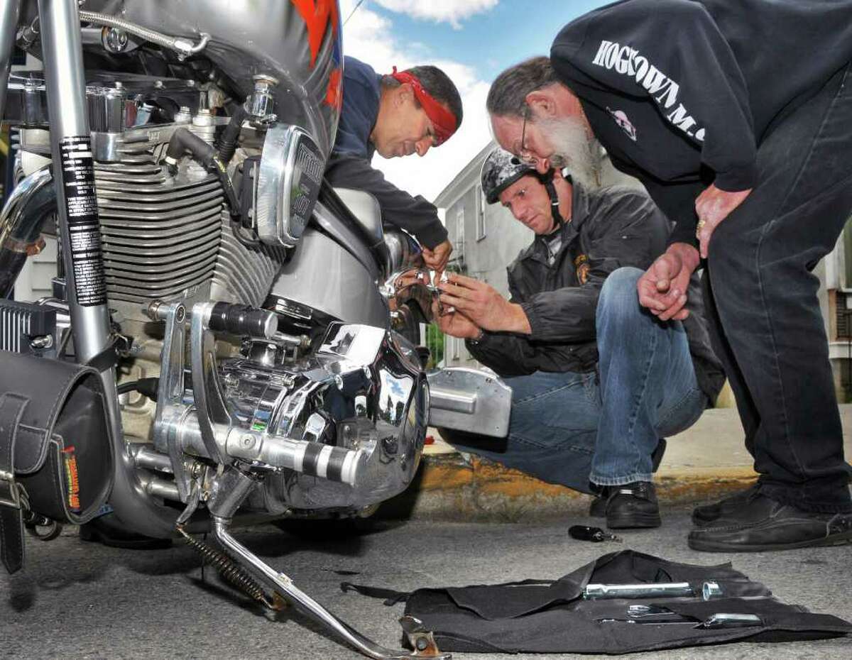 Victor John, right, of Lake George Hardware helps New Jersey bikers Gilly Six, left, and Bob Estelle work on Estelle's chopper June 8 in Lake George Village during the annual Americade. (John Carl D'Annibale / Times Union)