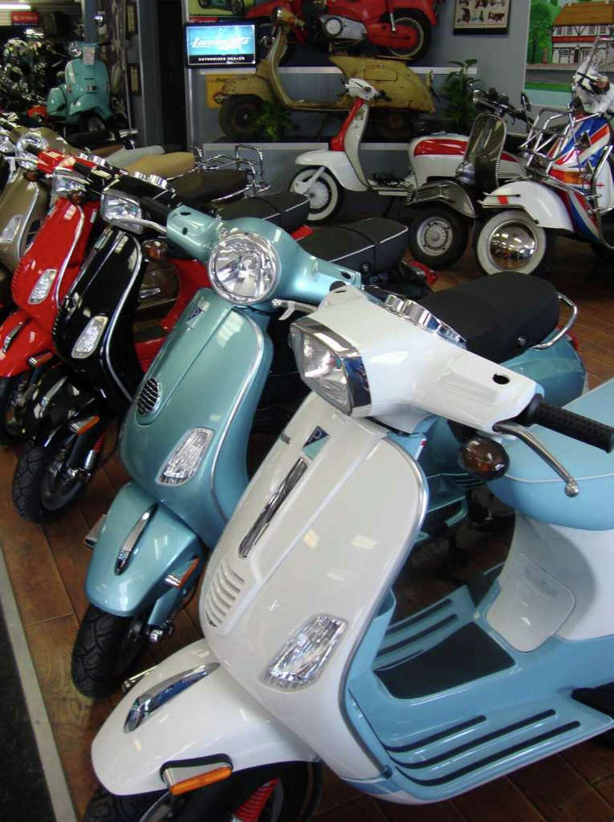 A row of new Vespa motor scooters sits in the showroom of The Motorcycle Shop on Austin Highway. These models have a top speed of about 65 mph and get about 70 to 80 mpg.