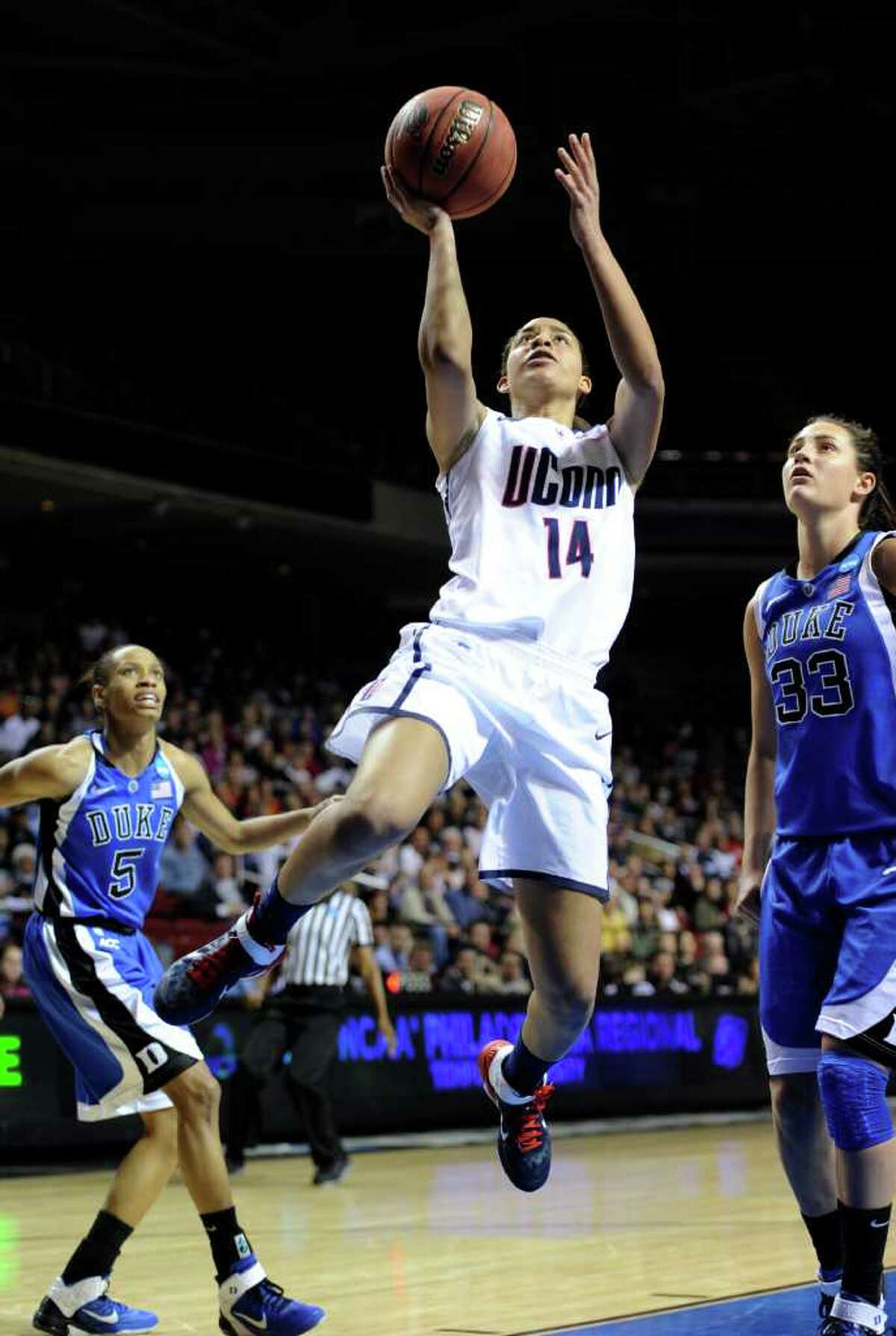 Connecticut's Bria Hartley (14) shoots past Duke's Jasmine Thomas (5) and Haley Peters in the first half of an NCAA women's college basketball tournament regional final game, Tuesday, March 29, 2011, in Philadelphia. (AP Photo/Barbara Johnston)