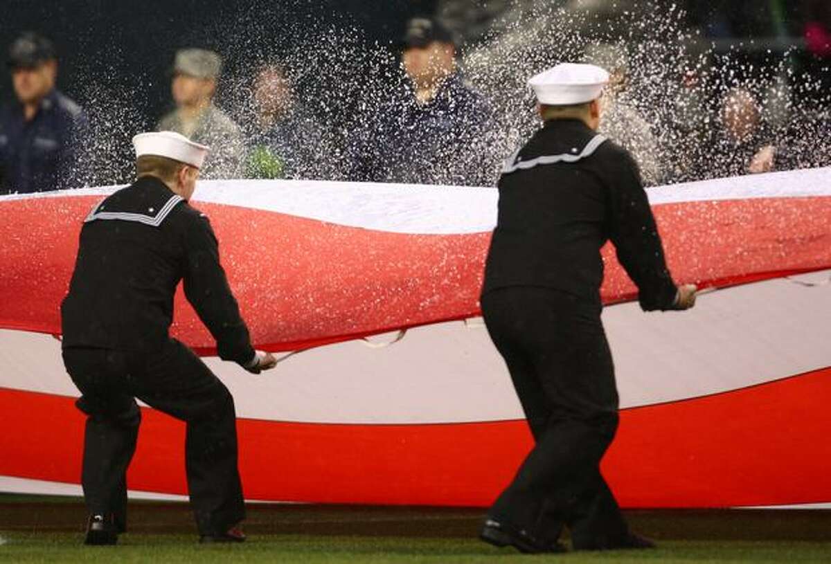 U.S. Navy seamen wave the U.S. flag, throwing water drops into the air, during pregame ceremonies as the Seattle Sounders and L.A. Galaxy kickoff the 2011 MLS regular season.