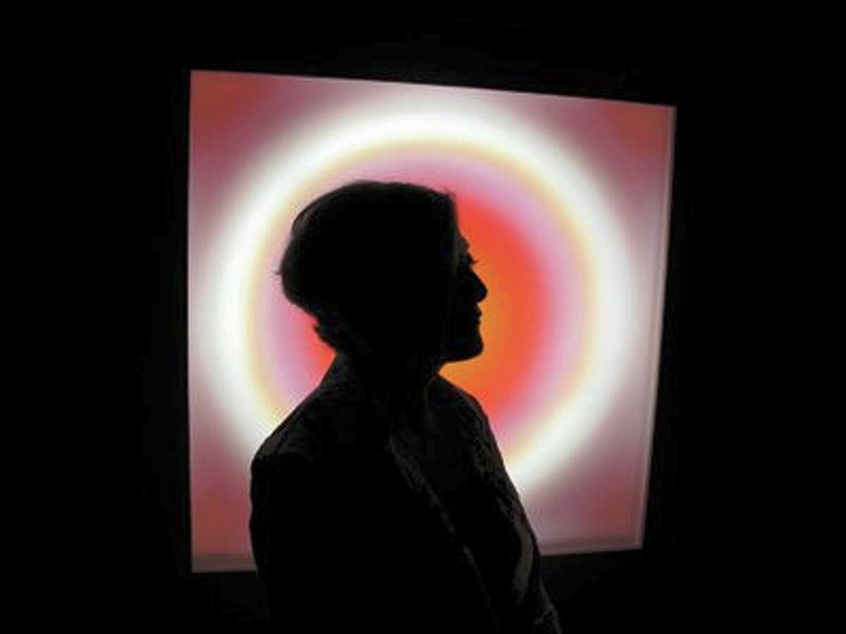 Cathy Cunningham-Little stands in silhouette in front of her multimedia neon work "Corona," on view in "Breathing Light" at the Blue Star Contemporary Art Center. COURTESY JOAN FREDERICK