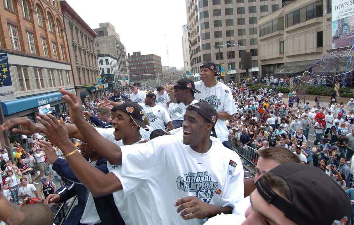 Emeka Okafor waves to the crowd with his University of Connecticut men's basketball teammates as they pass outside the Hartford Civic Center during the team's national championship parade in 2004. The Huskies can win their third national championship at Reliant Stadium in Houston with two more victories.