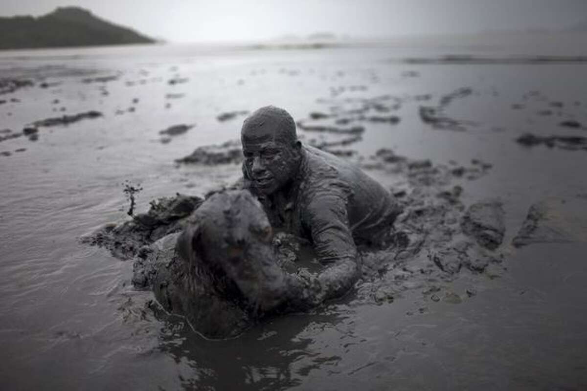 A man and his dog walk out after covering in mud as part of the "Bloco da Lama" (Mud Block) carnival group in Paraty, Brazil, Saturday, March 5, 2011. Brazil's official carnival is held this year March 4-8. (AP Photo/Rodrigo Abd)