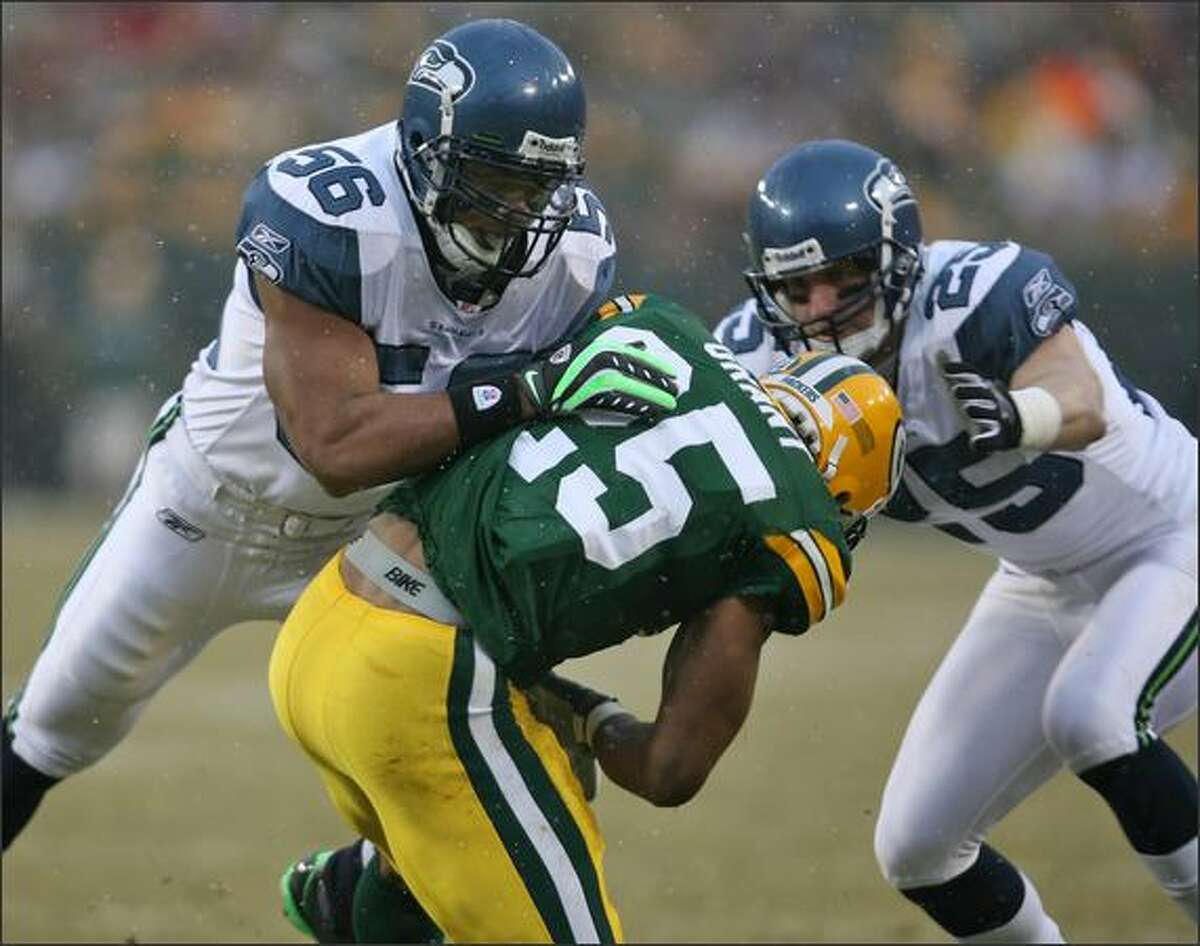 Seahawks linebacker LeRoy Hill and safety Brian Russell force Green Bay running back Ryan Grant to fumble the ball in the first quarter.
