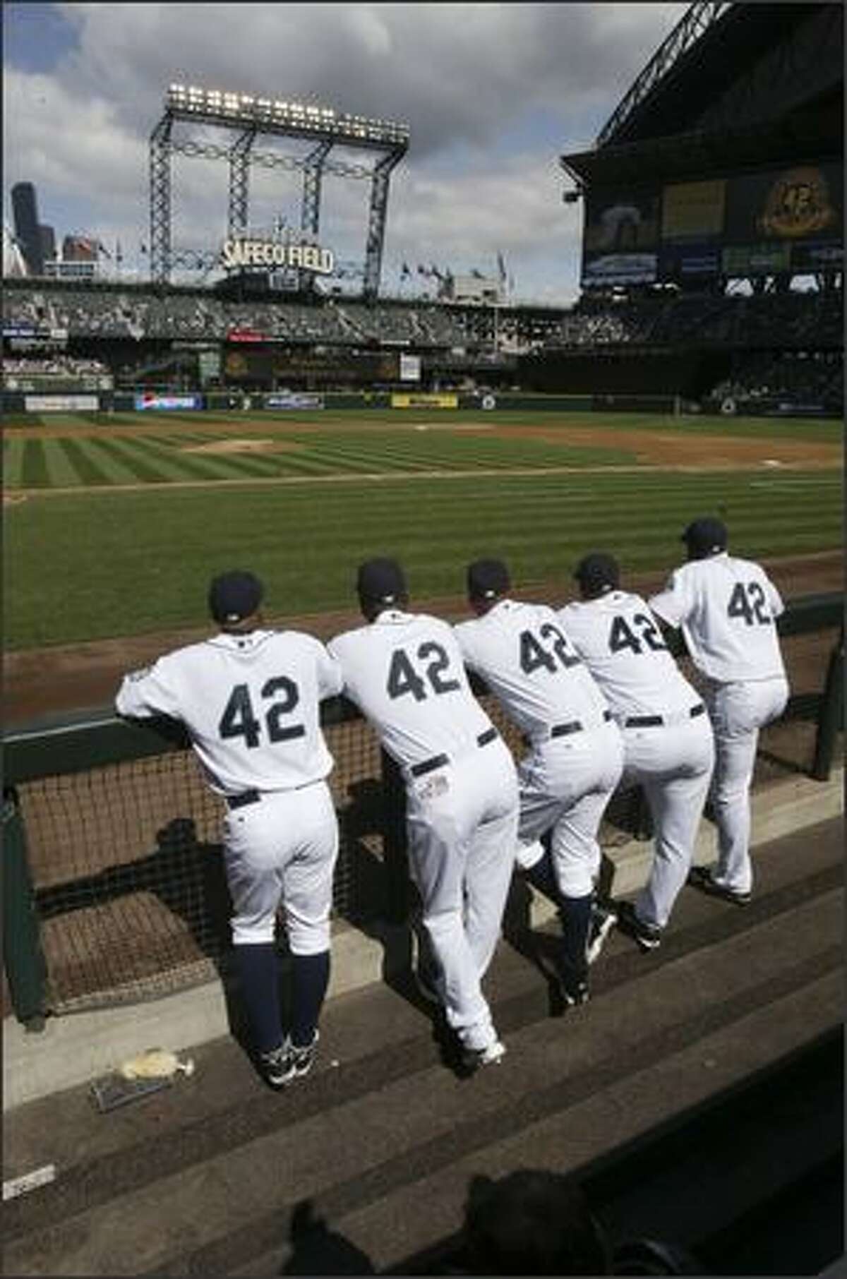 Mariners players -- from left to right -- Jason Ellison, Arthur Rhodes, Miguel Batista, Jose Lopez and Adrian Beltre line up in the dugout and watch a video tribute to Jackie Robinson as part of a ceremony commemorating the 60th anniversary of his breaking the color barrier in major league baseball. A number of Mariners and Rangers players wore Robinson's number 42 during the game.