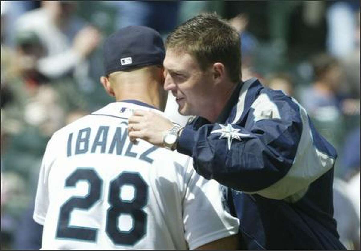 Former Seattle Mariners catcher Dan Wilson gives Raul Ibanez a hug after throwing out the ceremonial first pitch against the Kansas City Royals at Safeco Field Sunday.