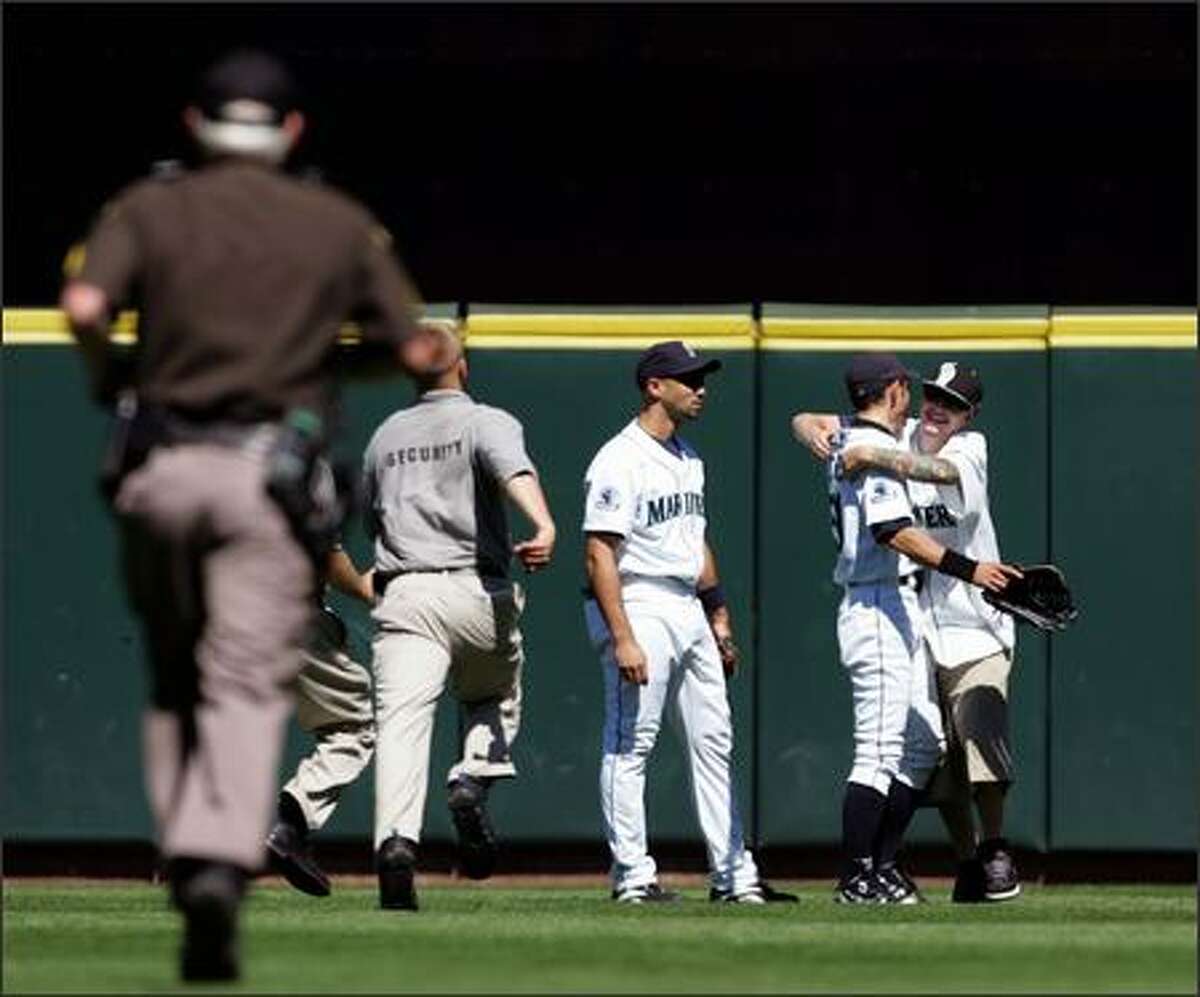 During a pitching change, Ichiro Suzuki gets hugged by a fan who ran onto the field and was taken into custody by security workers during the eighth inning of the Mariners' game against the Oakland Athletics. Seattle won 4-3. (AP Photo/Kevin P. Casey)