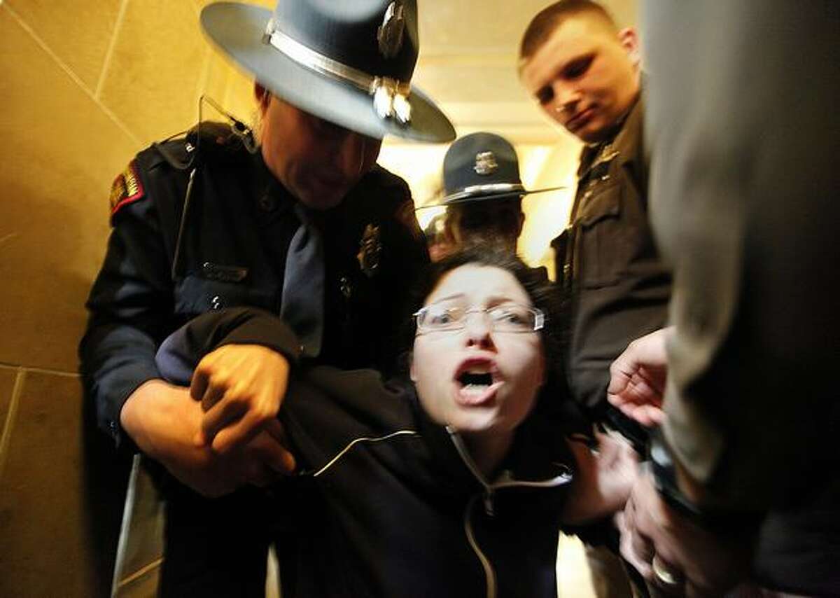 Elizabeth Wrigley-Field of Madison, Wis. is escorted out of the Wisconsin State Capitol Assembly Room lobby on Thursday in Madison, by law enforcement personnel after spending the night in the room with demonstrators opposed to Gov. Scott Walker's budget repair bill. Tensions have flared after Republican senators passed an amended version of the controversial bill which largely strips collective bargaining for public employees. (AP Photo/Wisconsin State Journal, John Hart)