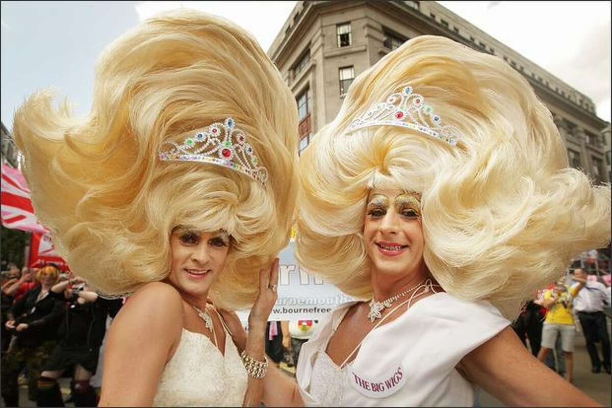 Two men in drag costumes pose at the Gay Pride parade in London. The parade consists of celebrities, floats, and performers celebrating the UK's largest gay and lesbian festival.