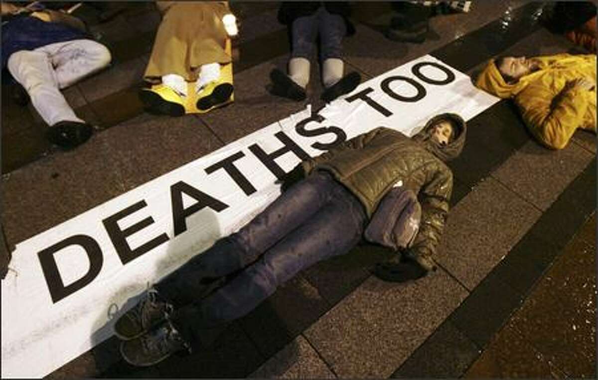 Carrie Hathorn, center, and Josh Farris, right, both of Seattle, lie on the ground during a "die-in" at Westlake Center with other Iraq war demonstrators.