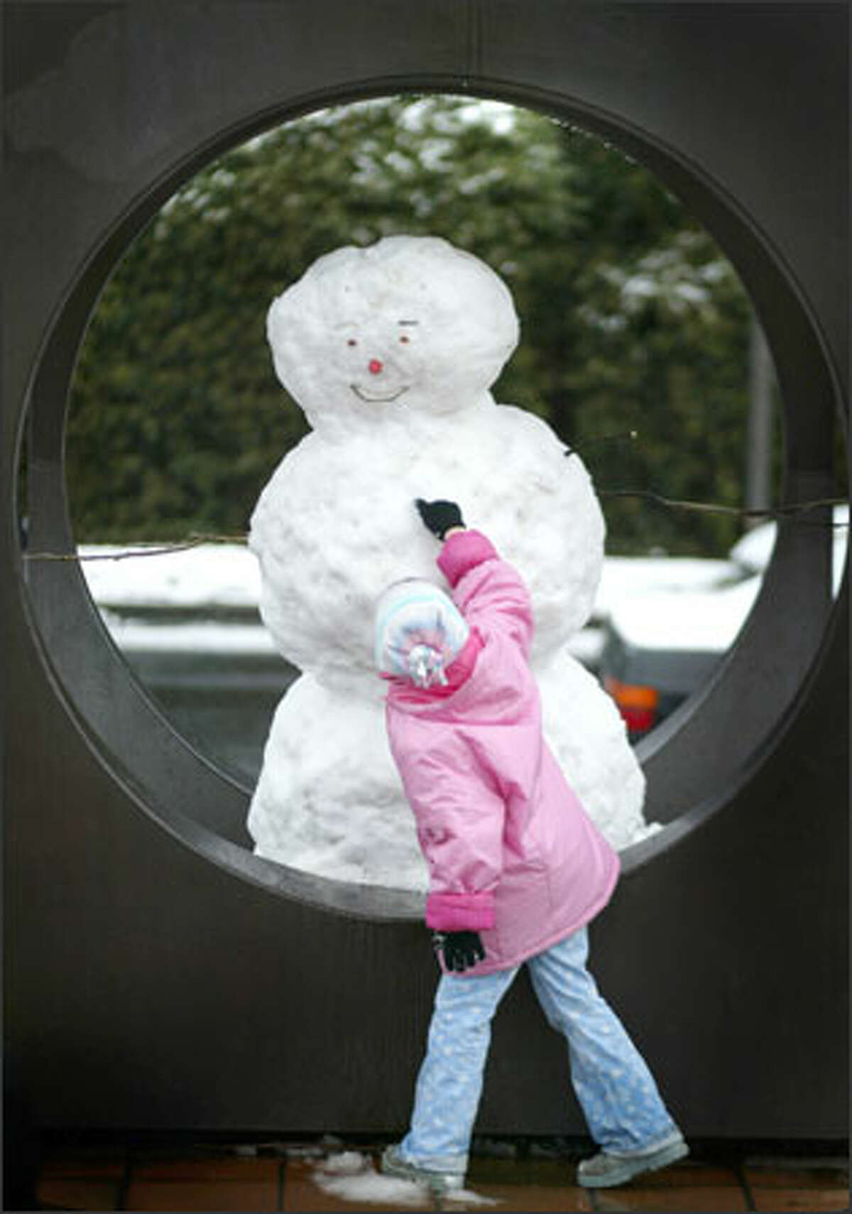 Sanuye Ford, 6, checks out the button of a snowman built inside the sculpture at Kerry Park on Queen Anne Hill. Seattle received a dusting of snow, with more of it falling north of downtown, early in the day. It brought out residents ready to play as well as city workers ready to plow and sand. The snow quickly melted.