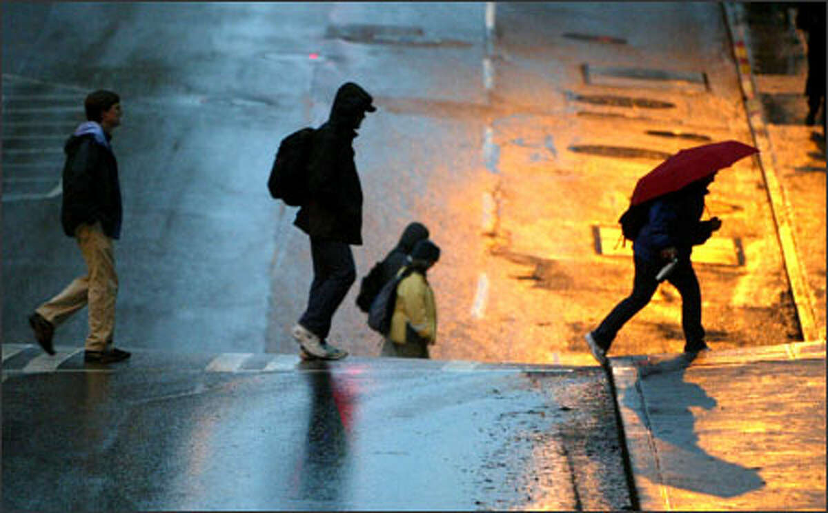 Pedestrians slosh across a street Tuesday in downtown Seattle. A State Patrol trooper grumbled about the long spell of wet weather, "This is getting dreary; I need sun!"