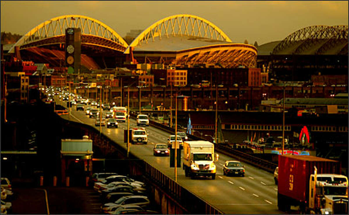 Traffic heads northbound on the Alaskan Way Viaduct at sunset, as the remaining light glows off Qwest Field in the background. The speed limit is 50 mph but an advocacy group wants to lower it for safety reasons.
