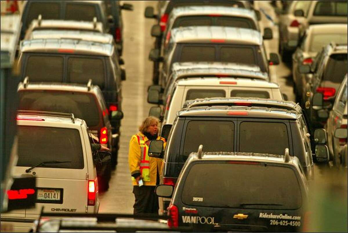 Ticket taker Chris Settles talks with a van pool driver in a long line of commuter vans waiting for the 5 p.m. ferry Issaquah at the Fauntleroy ferry dock.