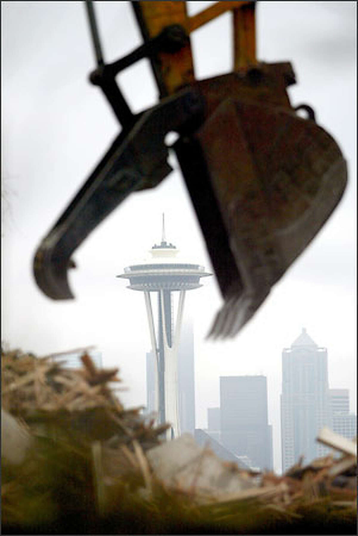 The jaws of a backhoe look as if they're about to devour the Space Needle as the operator works a pile of debris during demolition of a house on Queen Anne. The house at 222 W. Highland Drive sat across from Kerry Park Viewpoint and was built in 1914 for the J.C. Black family and designed by Andrew Willatsen, a protege of architect Frank Lloyd Wright. The house was sold last year and a permit was issued to demolish the house and garage to make room for construction of a single-family residence.
