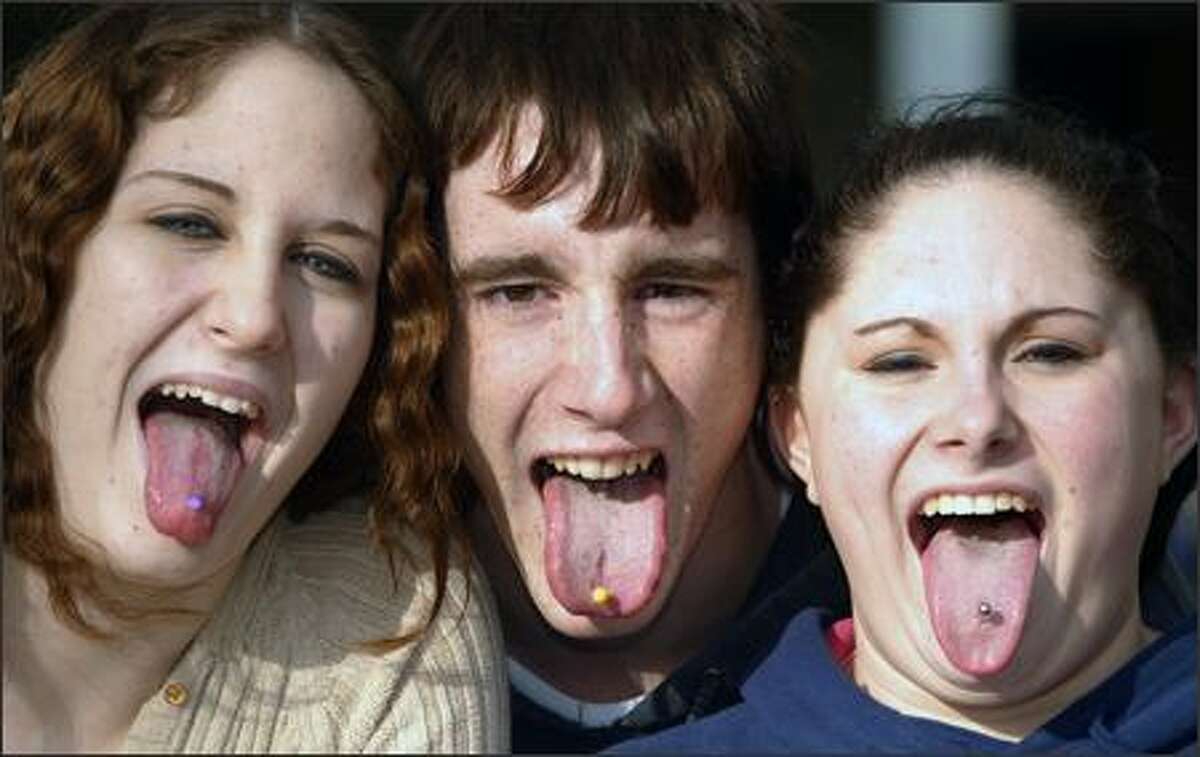 From left, Missy Golub, 17; Dylan Wood, 16; and Courtney Boker, 17, show off their tongue piercings, all done by piercer Kurtis Kirk of Golden Body Rings in the Green Lake area. Golden Body Rings, unlike most other shops, doesn't require parental permission for minors to get body piercings.