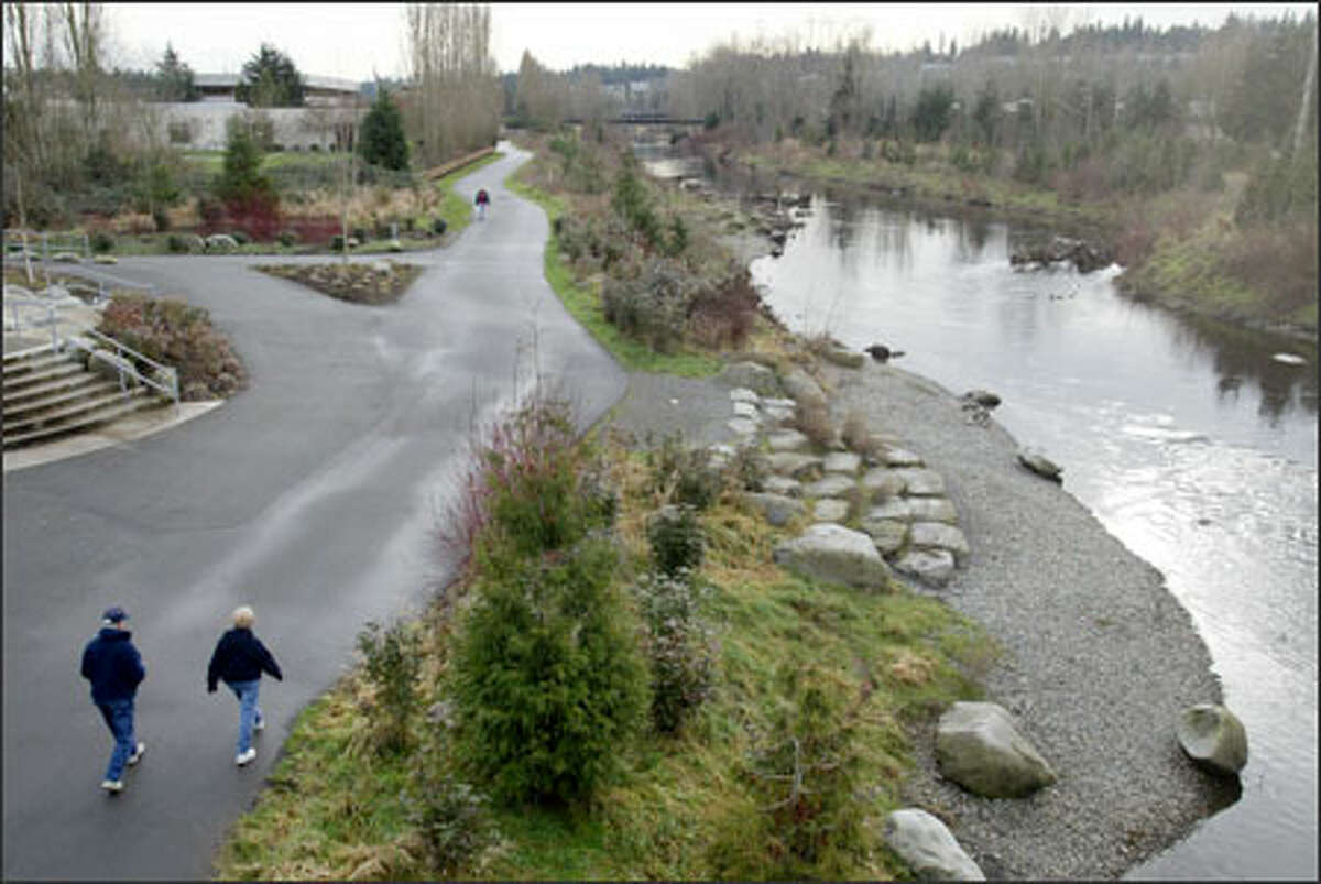 A man and woman stroll the RiverWalk in Redmond, where the Sammamish River is being transformed from "irrigation ditch" to nearer its original condition.