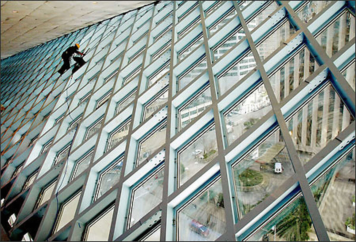 In a view from inside Seattle's new central library, Gabe Reisdorff vacuums construction dust from the windows at the top level of the building.