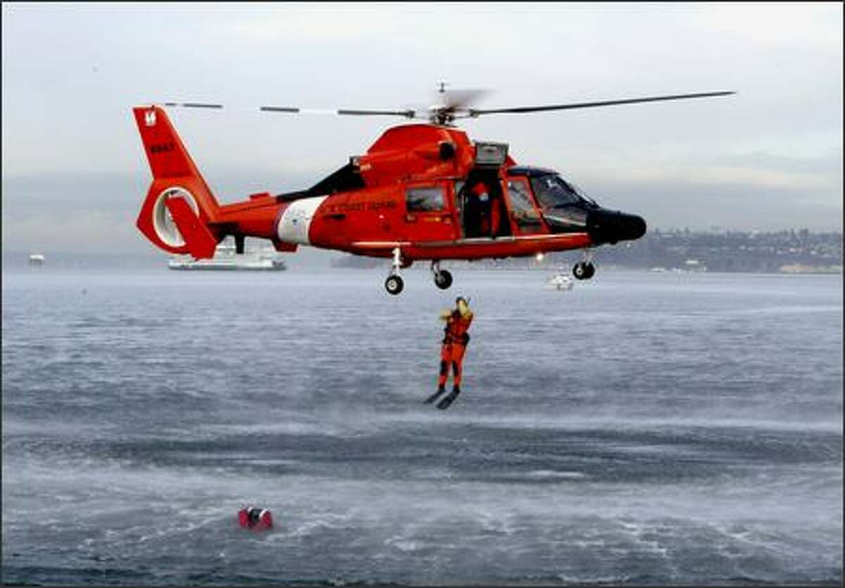 A U.S. Coast Guard rescue swimmer jumps from an HH-65 Dolphin helicopter into the Elliott Bay during a demonstration the agency's Pier 36 station. The Coast Guard hosted a visit by 39 first-graders from Hawthorne Elementary through the Partnership in Education Program.