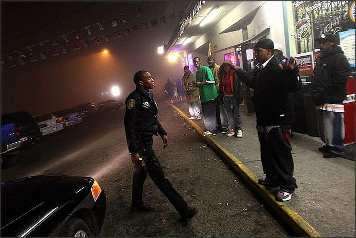 Seattle Police Officer Adley Shepherd approaches a young man in front of the bar Champs while on patrol in the south end of Seattle.