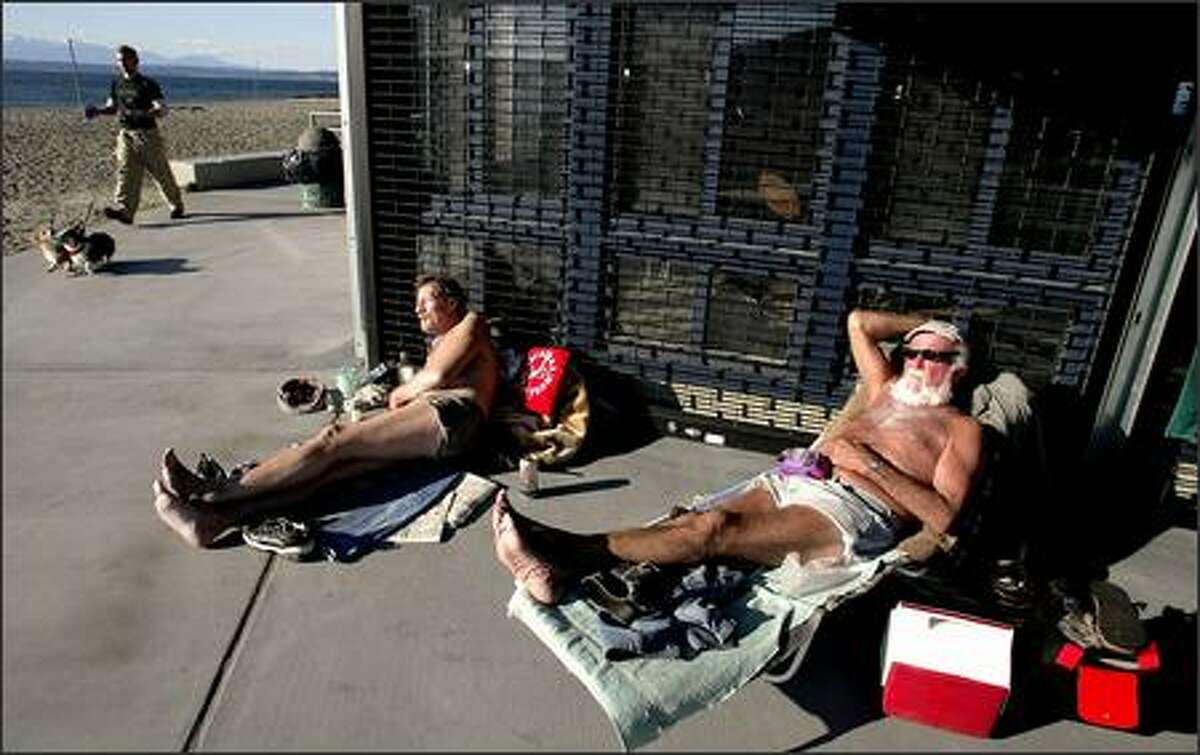 Art Foss, right, and Al Ochs use a building for a windbreak as they sunbathe at Golden Gardens Park. Temperatures hovered Wednesday around 45 degrees, but chillier weather is expected for the rest of the week.