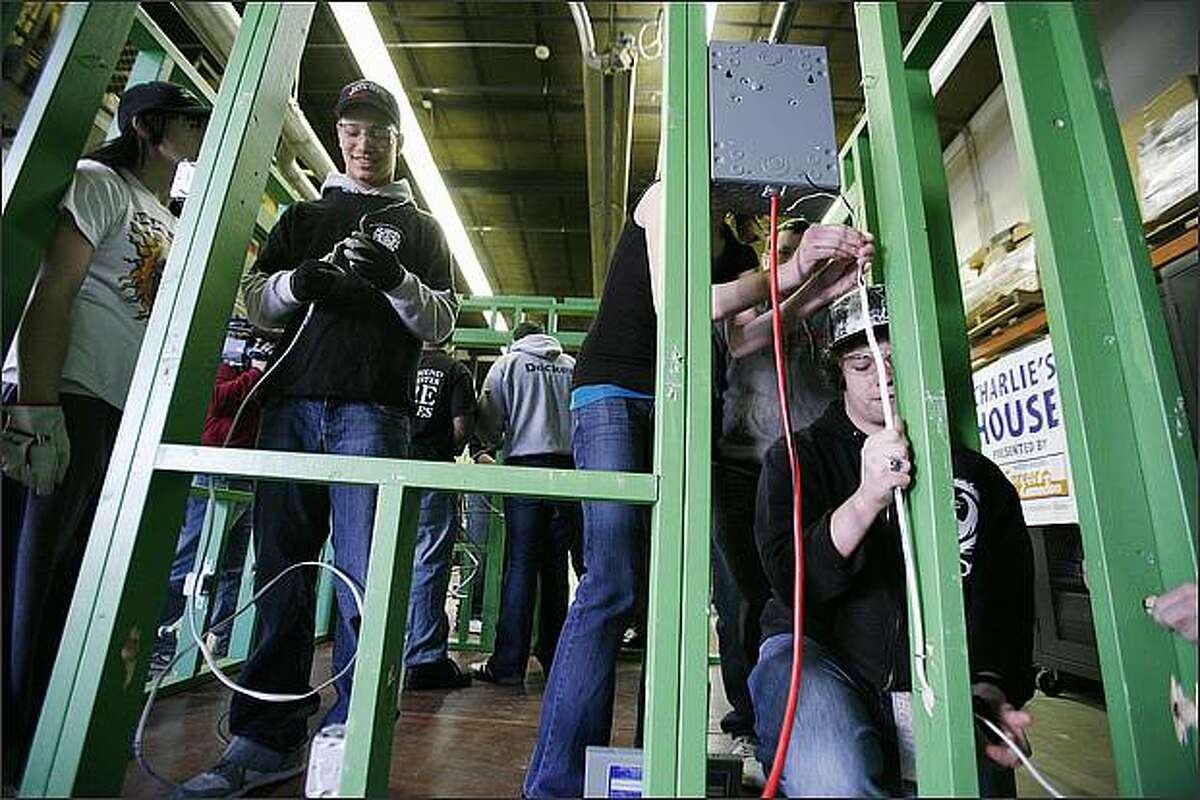 Cameron Harris, 18, running wiring through the frame of "Charlie's House," a 9x11 structure used to teach building trades at the Puget Sound Skills Center in Burien. The program is run by Master Builders Association of King and Snohomish Counties.
